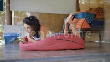 巴厘岛上的活动。 一个短发女孩，穿着白色t恤，躺在柔软的红色垫子上，还有一个
